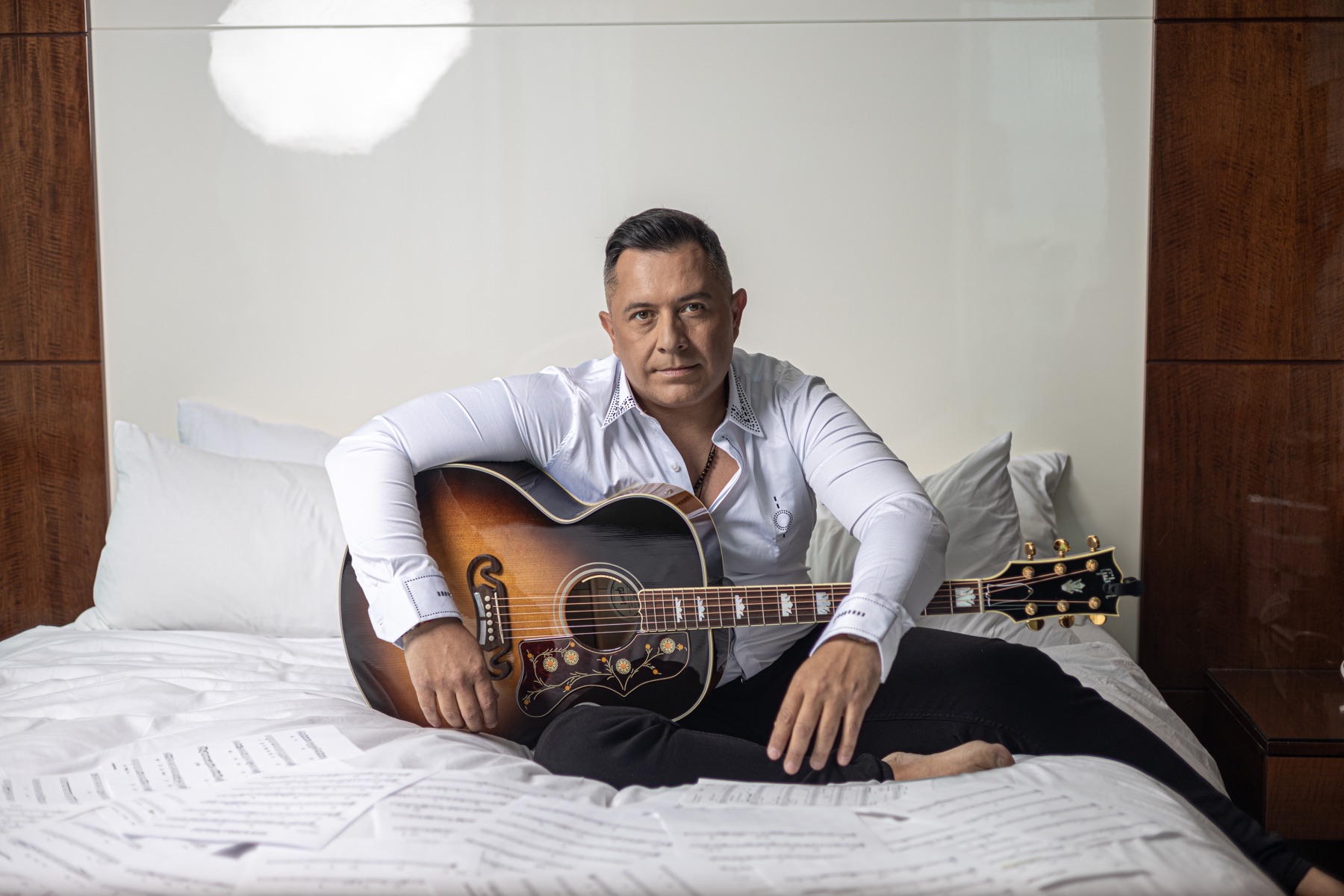 Astor Torres recostado con su guitarra sobre partituras